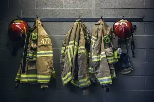 Firefighter gear ready for action: protective jackets and helmets hanging on a wall, symbolizing preparedness for emergency response.